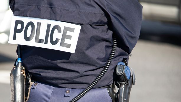 The back of the police officer with the inscription "POLICE" with a gun and a walkie-talkie. Investigation de l’homicide d’une octogénaire au Grau-du-Roi