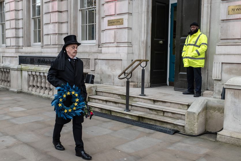 A man wearing an undertaker's attire, holding an 'EU' wreath, walks past the Cabinet Office on Whitehall. Une Nouvelle Ére pour les Relations entre l’UE et le Royaume-Uni