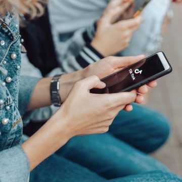 People use a smartphone while sitting on a bench in the street. Le Brésil renforce sa régulation des plateformes numériques