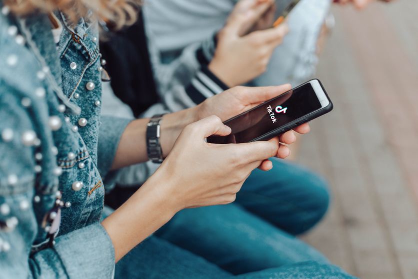 People use a smartphone while sitting on a bench in the street. Le Brésil renforce sa régulation des plateformes numériques